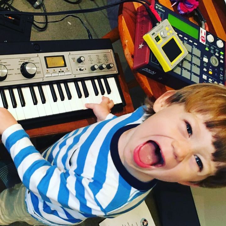 A little boy laughing at a keyboard
